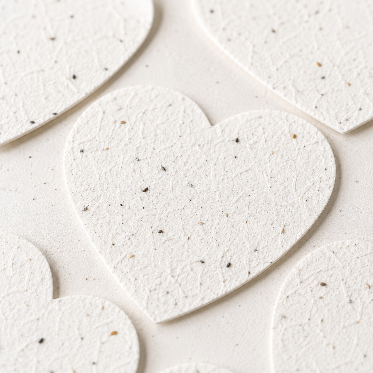 Close-up of handmade plantable seed paper hearts showing natural texture and embedded wildflower seeds in recycled paper.